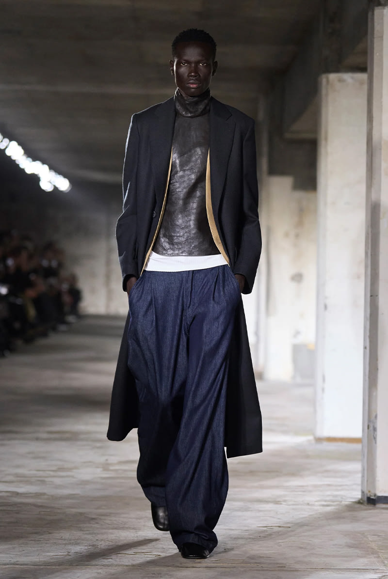 Wide jeans styled with a textured black turtleneck sweater, long dark coat, and leather boots.