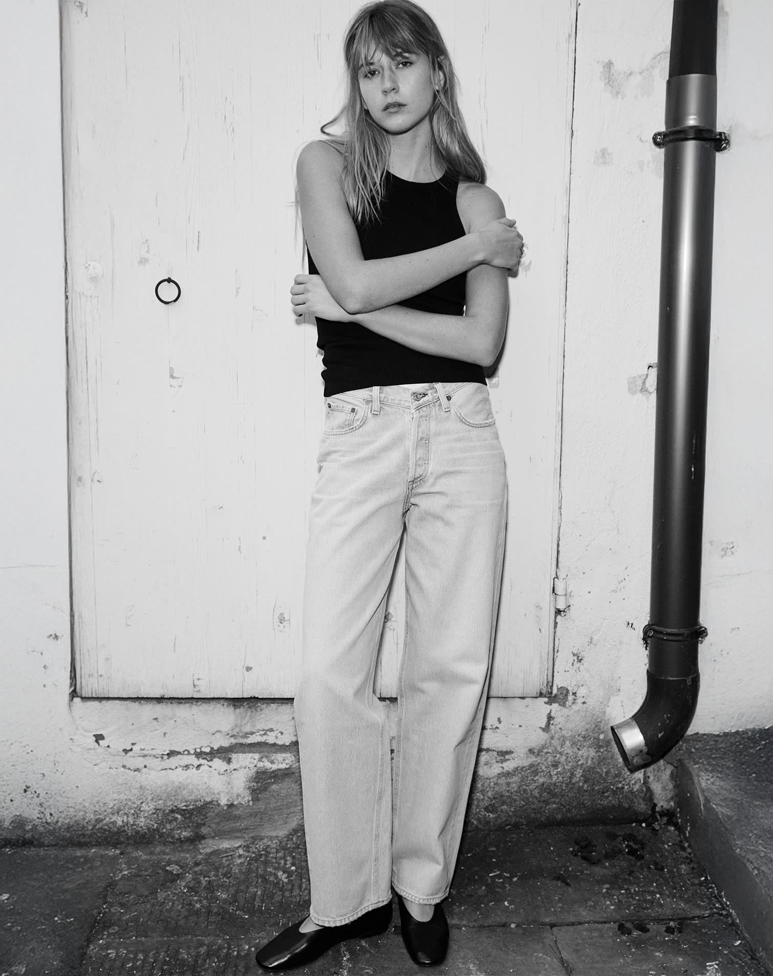 Modella indossa outfit casual con top senza maniche nero e jeans in denim bianco